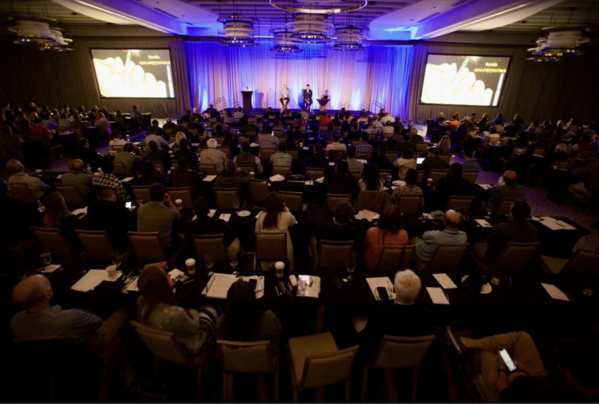 A packed Strupp & Brumm CE seminar ballroom in Clearwater, Florida — hundreds of dentists, both doctors on stage, dual-screen presentation